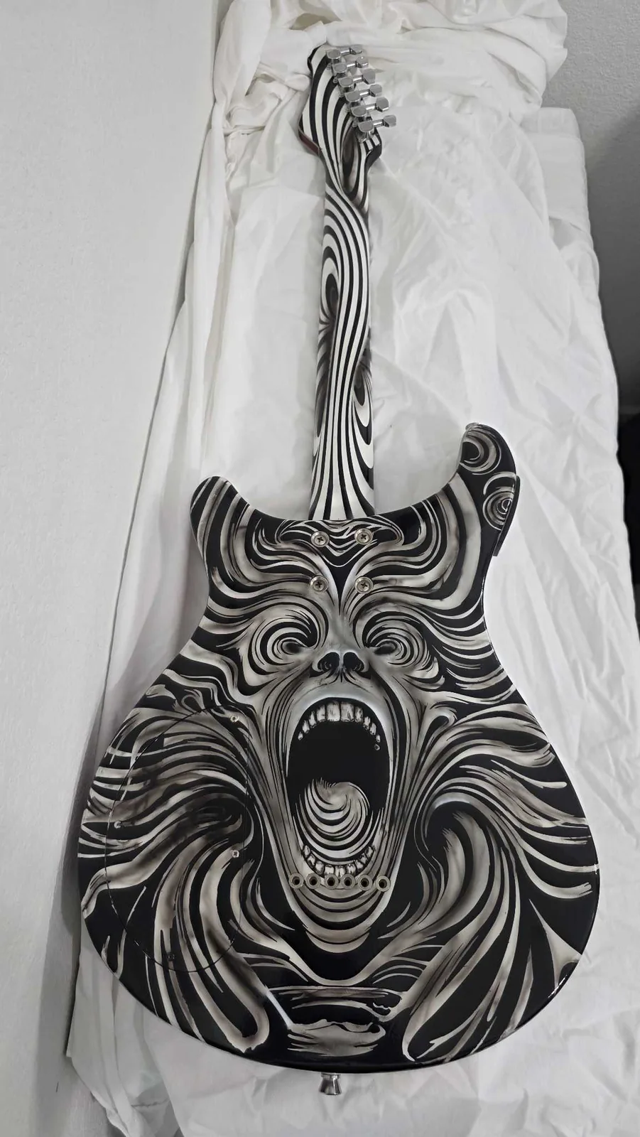 The carved and painted reverse of the guitar, a screaming face surrounded by flowing hair